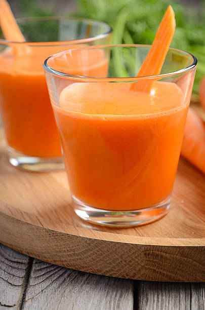 istock Fresh carrot juice on wooden background 587773142