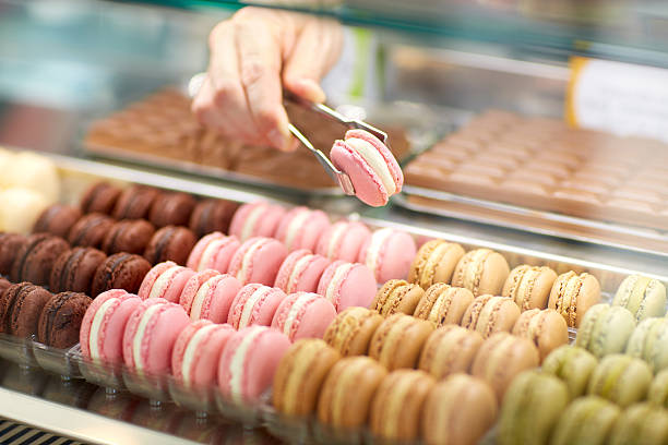 Taking out macaron from glass case Sellers hand taking out macaron from glass case display cabinet stock pictures, royalty-free photos & images