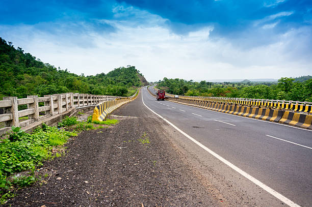 istock Empty road borded by  hills with cloudy skies 587774220