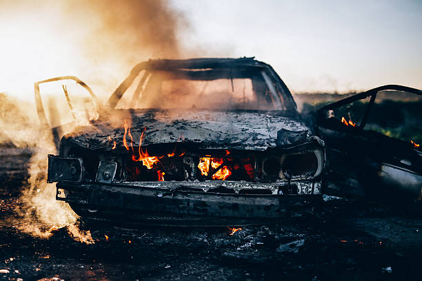 Burnt car with small flames inside of the engine