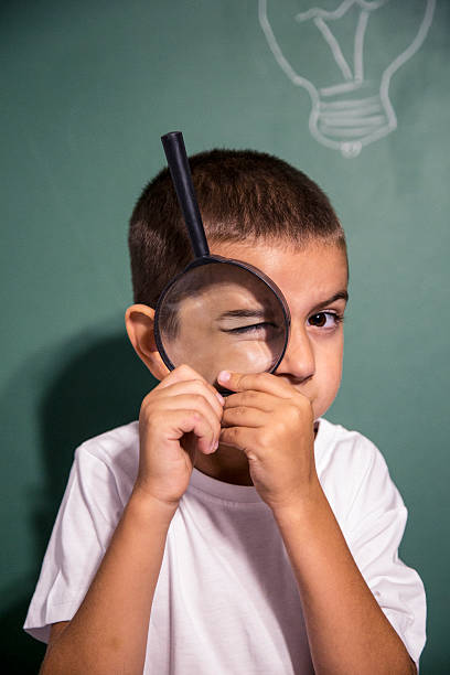 istock Little boy looking at camera through magnifying glass 587780114