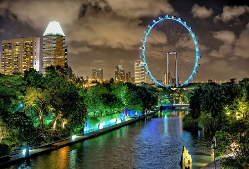 Singapore, Singapore - February 29, 2016: Singapore Flyer and skyline of Downtown Core at Marina Bay at night. Skyscrapers and Ferris Wheel illuminated with light and reflected in the water