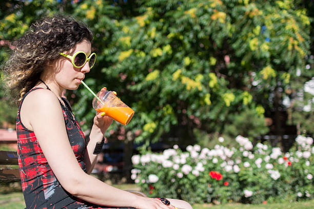 istock Young girl drinking orange cocktail with a straw 587785490