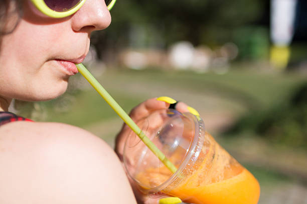 istock Young hipster girl drinking orange smoothie 587785752