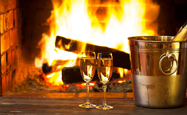 Sparkling wine in front of warm fireplace. Romantic, cozy atmosphere