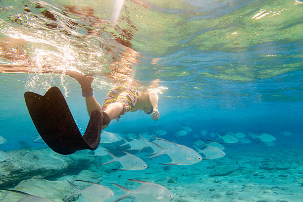 Young man swimming with fishes.