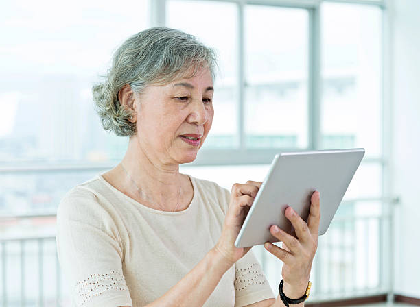 istock Asian senior woman using a digital tablet at home 587795280