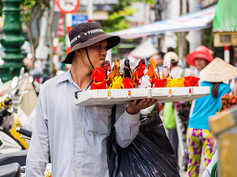 Ho Chi Minh, Vietnam - June 28, 2012: A man selling colorful bobblehead car ornaments in the streets of Ho Chi Minh, Vietnam.
