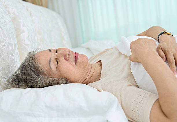 istock Senior woman lying in bed sleeping 587796806