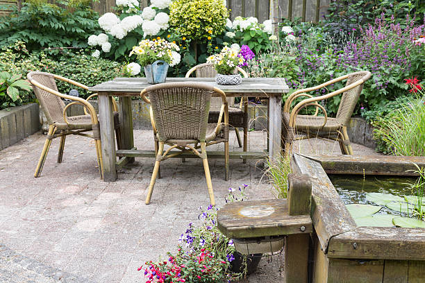 Wooden table and chairs in a ornamental garden Wooden table and chairs in a ornamental garden with pond palisade boundary stock pictures, royalty-free photos & images