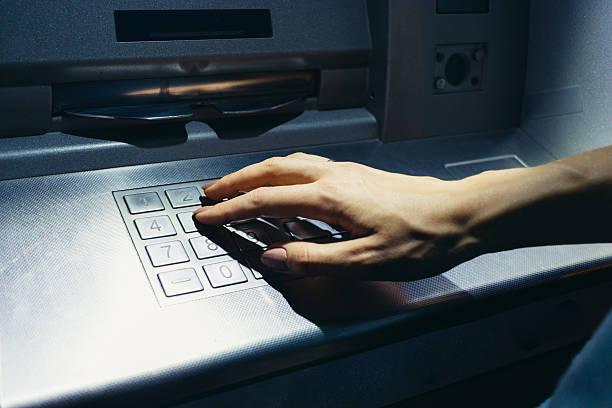 Woman's hand enters the code at the ATM at night Woman's hand enters the secret code at the ATM on the street at night exchange teller stock pictures, royalty-free photos & images