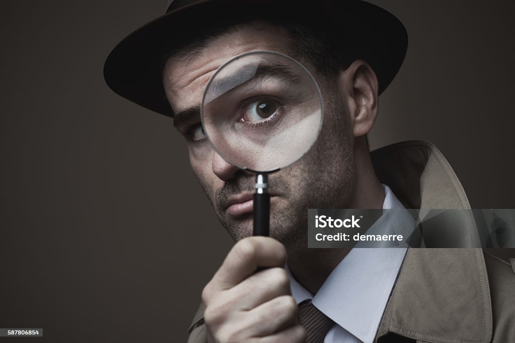 Vintage detective looking through a magnifier Funny vintage detective looking through a magnifier Adult Stock Photo