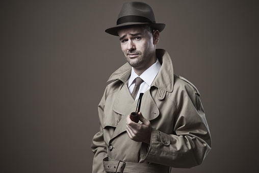 Funny vintage investigator in trench coat holding a pipe
