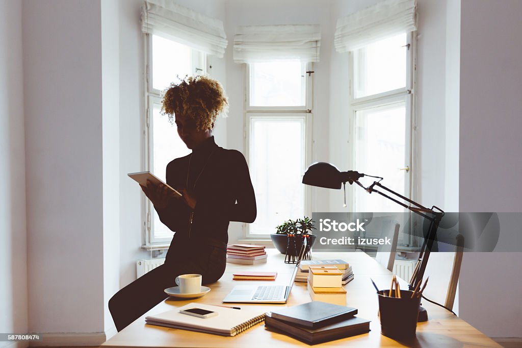Afro american woman using a digital tablet in an office Afro american young woman using a digital tablet in a home office. Marketing Stock Photo