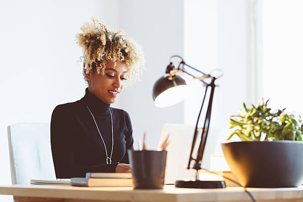 istock Afro american young woman using a laptop in an office 587809880