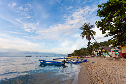 Puerto Galera, Philippines - May 15, 2012: Beachside scene in Sabang Beach in Puerto Galera, Philippines. Boats can be seen docked by the shore and people can be seen walking around.
