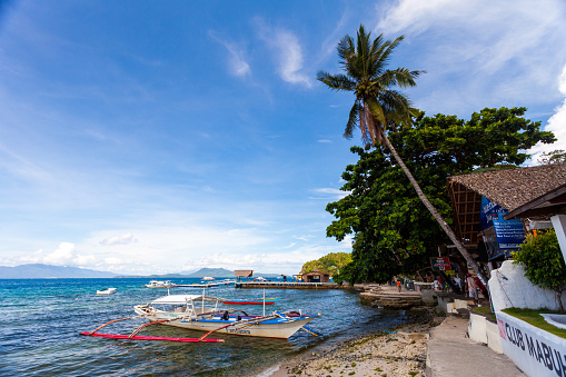 Puerto Galera, Philippines - May 15, 2012: Beachside scene in Sabang Beach in Puerto Galera, Philippines. Boats can be seen docked by the shore and people can be seen walking around.