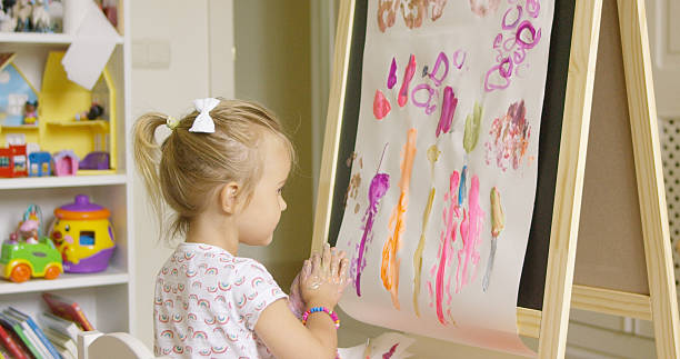 istock Artistic little girl painting a creative design 587810342