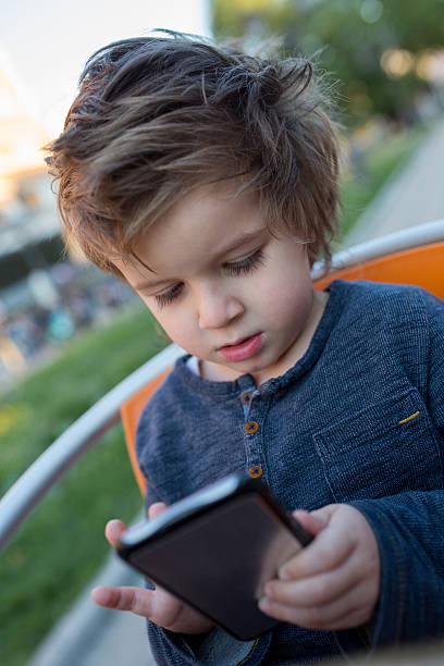 istock Cute little boy texting on cell phone. 587812346