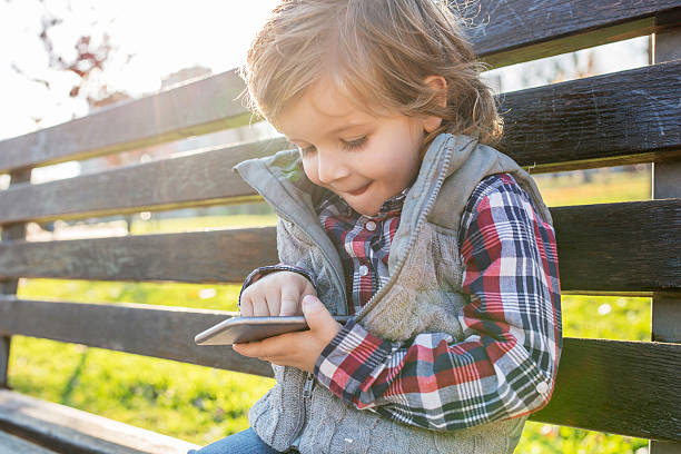 秋の公園でテキストメッセージを入力する小さな男の子。 - child text messaging little boys male ストックフォトと画像