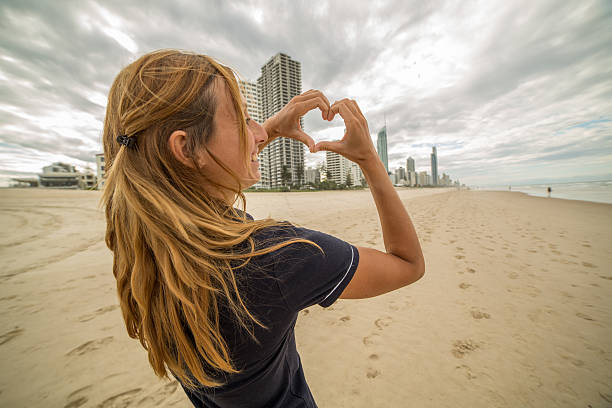 istock Young woman frames Surfer's paradise beach into heart shape 587813044