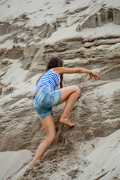 istock girl climbing on the sand 587813448