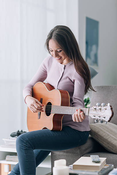 istock Girl playing guitar at home 587817450