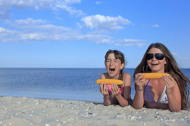 istock Happy children on the beach eating sweet corn. 587817612