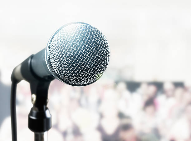 shiny brightly lit microphone with background audience - brightly lit audio imagens e fotografias de stock