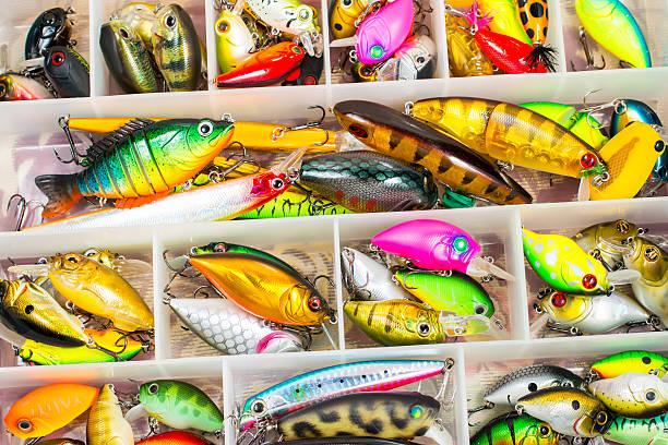Colorful fishing lures and accessories in the box background Colorful fishing lures and accessories in the box background crank mechanism photos stock pictures, royalty-free photos & images