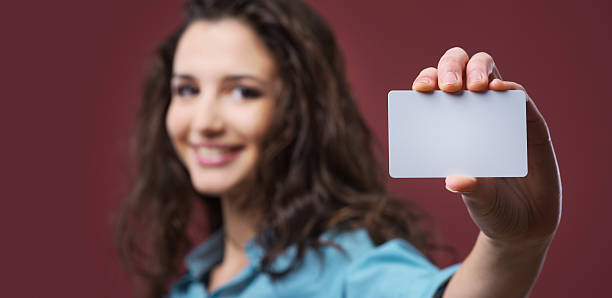 mujer joven sosteniendo una tarjeta de negocios - smiling business card horizontal women fotografías e imágenes de stock