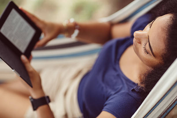 Woman resting in a hammock Young girl resting and reading an e-book outside hammock relaxation women front or back yard stock pictures, royalty-free photos & images