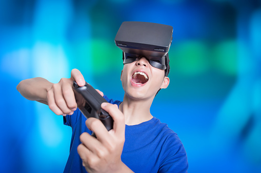 Young man surprised expression with virtual reality headset and play 3d gmae, isolated blue background, asian