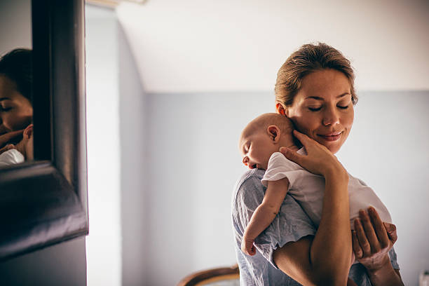 Sleeping Newborn A happy new mother smiles as she craddles her sleeping baby in her arms. She has her eyes closed as she holds her close. newborn stock pictures, royalty-free photos & images