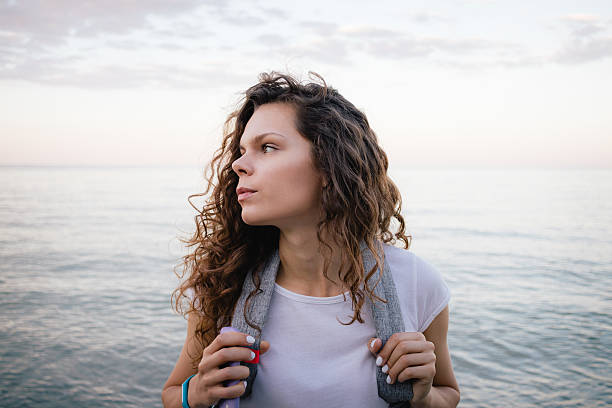 istock Curly brunette with a backpack standing near the water 587876644