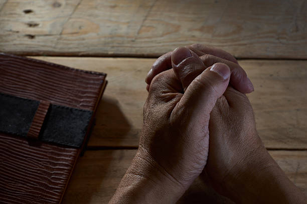 istock Close up on mans hands folded in prayer . 587879834