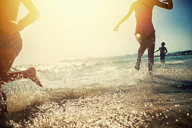 Brothers and sister running on beach on sunset