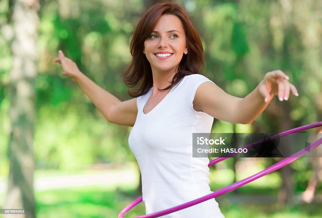 Woman rotates hula hoop on nature background Hooping Stock Photo