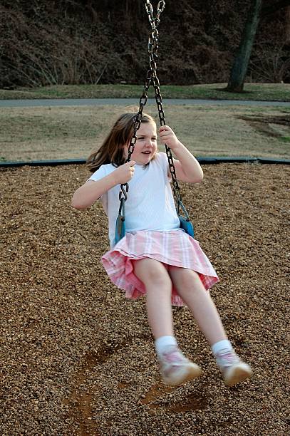 istock young girl spinning on a swing in a park 587886864