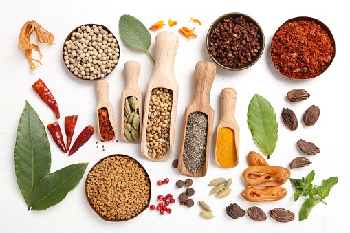 Colorful spices and herbs on white wooden background.