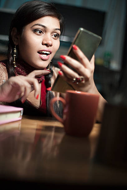 istock Girl on study table with books coffee mug using smartphone. 587891668
