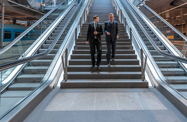 hablando de empresarios caminando por las escaleras en la estación de ferrocarril moderna - stair rail fotografías e imágenes de stock