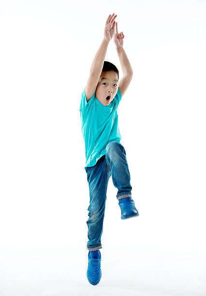 giovane ragazzo asiatico che salta su sfondo bianco - arms raised green jumping hand raised foto e immagini stock