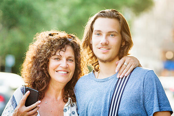 Mother and teenaged son Summer urban portrait with phone Mother and teenaged son Summer urban portrait with phone, back lit by sunset. canadian culture photos stock pictures, royalty-free photos & images