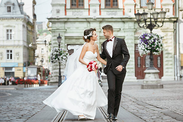Married couple walking in the city and holding bouquet stock photo