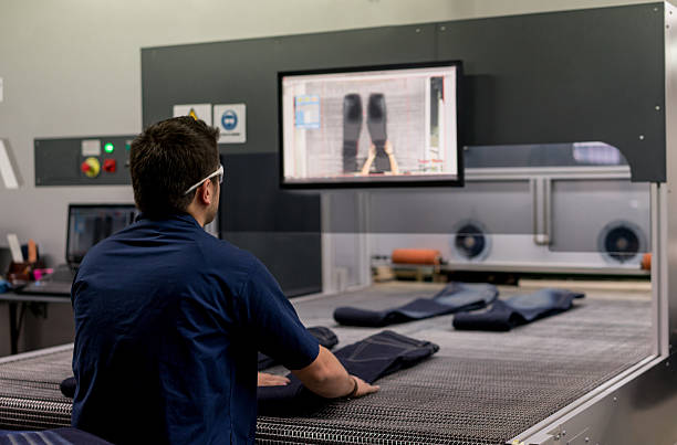 Man operating a laser machine at a clothing factory