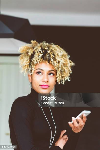 Afro American Young Woman Holding A Smart Phone Stock Photo - Download Image Now - Smart Phone, Asking, Contented Emotion