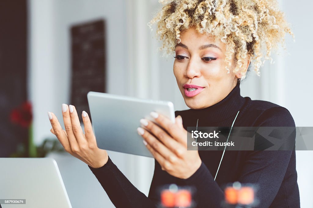 Afro american young woman using digital tablet in an office Beautiful afro american young woman using a digital tablet in an office. Discussion Stock Photo