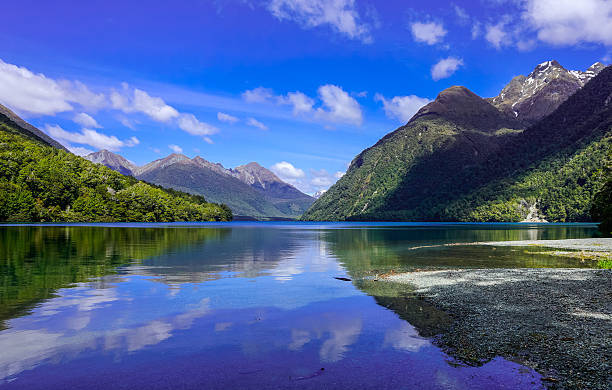 Beautiful reflection of clear blue sky on Mirror Lake Image reflected in water or Mirror Lake, Milford Sound New Zealand milford sound stock pictures, royalty-free photos & images