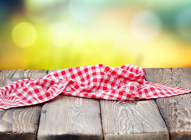 istock Red picnic cloth on wooden table mature bokeh background. 587931158